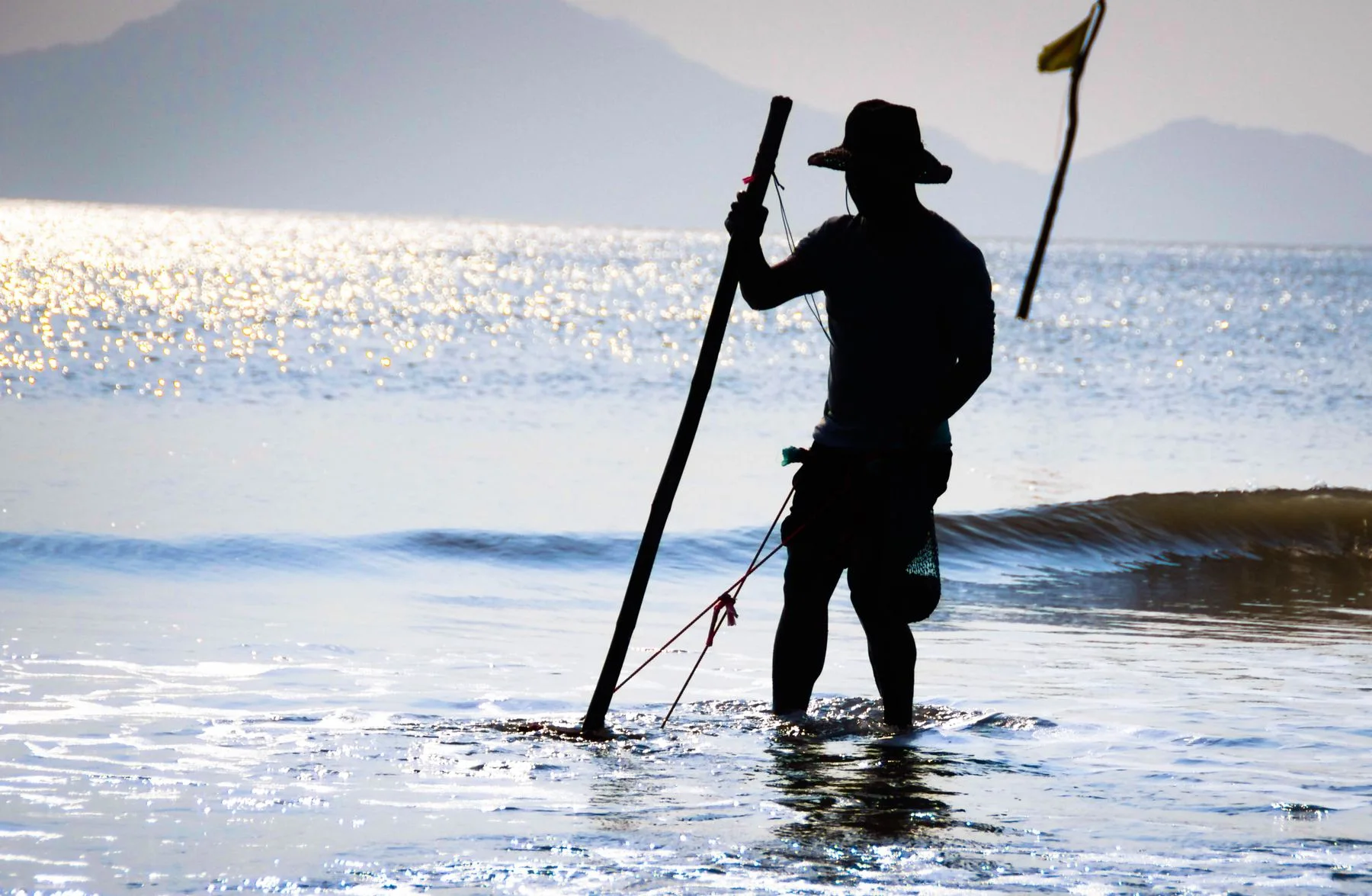 A silhouetted angler standing in shallow sea water