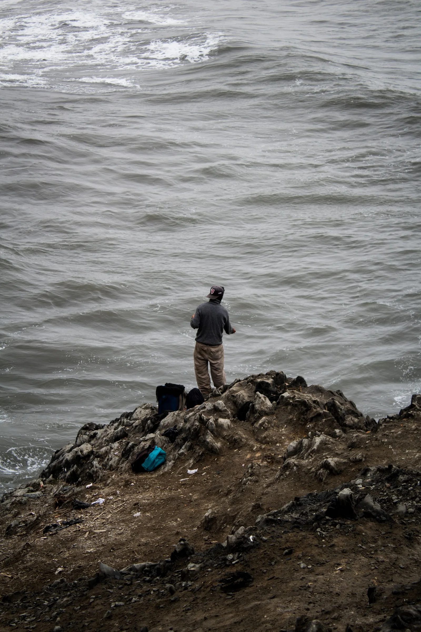 An angler looking out over a rocky coastline